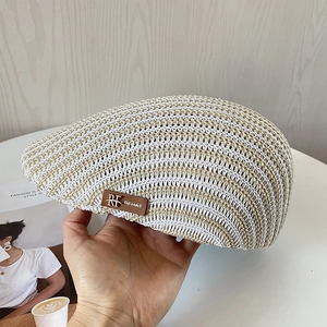 Dettaglio cappello newsboy in maglia beige con trama traforata e logo in pelle RFHAT