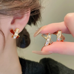 Detail of cross geometry earrings with gold plating, zircon inlay, and red enamel accents