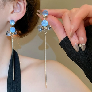 Close-up of elegant long silver tassel earrings with blue resin beads on a female model