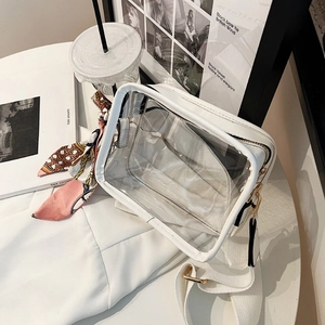 Macro shot of white transparent PVC crossbody bag with silk scarf and gold hardware detail