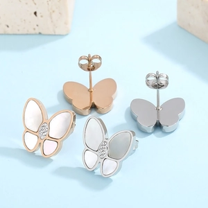 Detailed view of rose gold and silver butterfly studs with shell inlay and crystals