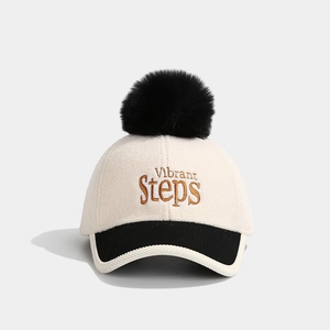 Close-up of beige wool baseball cap with black pompom and Vibrant Steps embroidery