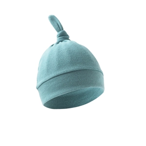 Detail of teal blue knitted newborn hat with a top knot design on white background