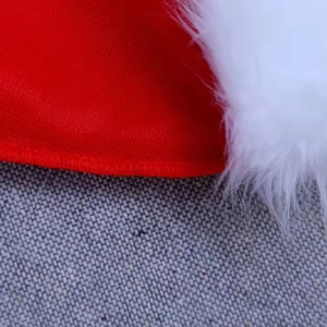 Close-up of red fabric texture and white plush trim stitching on a Christmas hat
