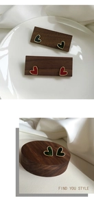 Detailed macro view of S925 heart earrings in emerald green and red enamel with gold edges