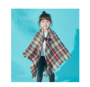 Detail of classic plaid kids poncho featuring wood horn buttons and fringe tassels