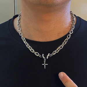 Primo piano di una collana con pendente a croce in acciaio titanio argento sul collo