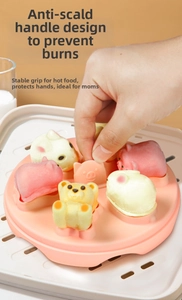 Pink silicone baby food mold with bear shapes and anti-scald handle inside a steamer