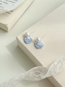 Detail of silver stud earrings with white pearl and blue ice-crackle cloud pendants