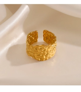 Macro shot of gold wide hammered texture ring on elegant white silk fabric background