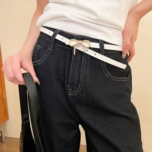 Close-up of white leather bow belt with gold metal buckle on a model's waist