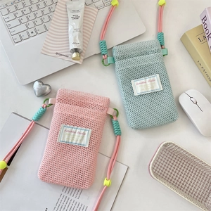 Detailed view of pink and mint green mesh phone bags with woven straps on a desk