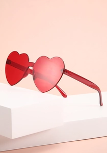 Close up of trendy red heart-shaped sunglasses, stylish party eyewear detail shot.