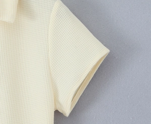 Detailaufnahme der beigen Polo-Kleid-Waffelstruktur und der genähten Ärmelkante