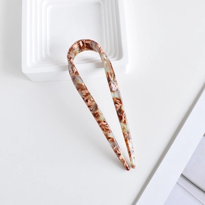 Close-up of a U-shaped acetate hair pin featuring a brown and beige tortoise shell pattern
