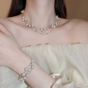 Detailed close-up of a three-layer pearl necklace and matching bracelet set on model