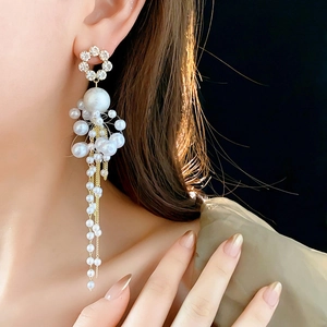 Detail of long fringe pearl earring featuring a rhinestone flower and golden finish