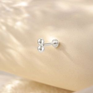 Detailed macro view of a silver cartilage earring with double ball design and flat disc back