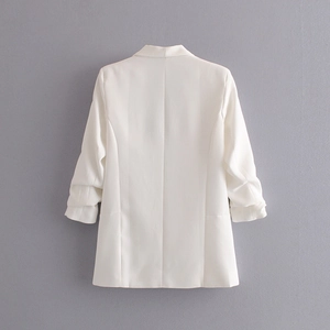 Detalle de chaqueta blanca con mangas tres cuartos fruncidas y diseño de espalda limpia