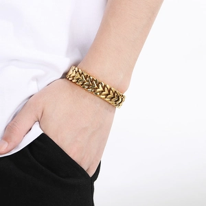 Détail d'un bracelet doré à maillons en forme de cœur entrelacés porté au poignet