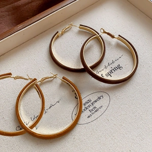 Detail of vintage brown leather-wrapped hoop earrings on a canvas display background