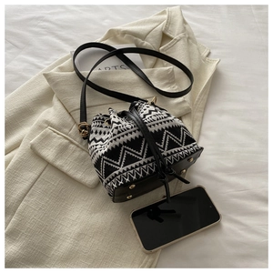Close-up of geometric pattern bucket bag with golden hardware on a beige blazer