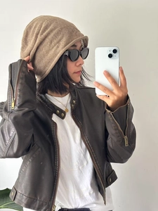 Close-up of a brown knit slouchy beanie paired with a vintage leather jacket and sunglasses