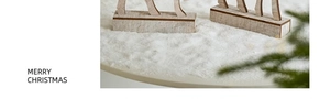 Close-up of wooden Christmas reindeer figurine on artificial snow with rustic pine detail