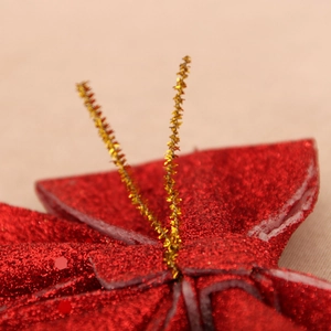 Close-up of red sequined Christmas bow with gold metallic ties for festive tree decoration