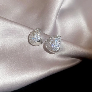 Macro shot of silver teardrop stud earrings with pavé zircons on soft silk background