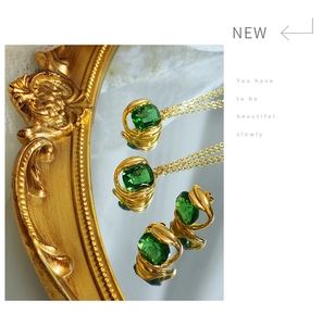 Close-up of emerald green crystal pendant necklace and earrings on a mirror surface