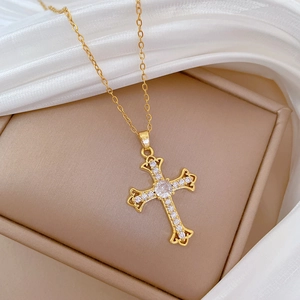 Macro view of gold cross pendant with sparkling crystals on beige jewelry box