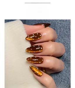 Vue macro de faux ongles amande effet œil de chat marron avec des pois blancs