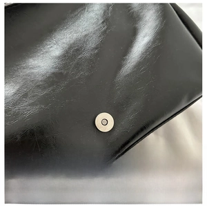 Close-up of high-quality magnetic clasp hardware on a vintage black oil leather bag