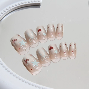 Cute French press-on nails with red bows, stars, and heart patterns on nude pink base