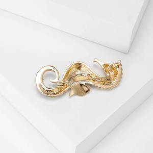 Creative golden seahorse brooch with pearl accent on a minimalist white background