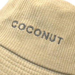 Detail of corduroy bucket hat in beige featuring dark grey COCONUT letter embroidery