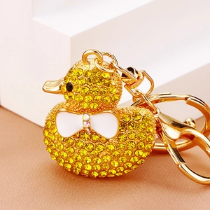 Detailed macro view of yellow rhinestone duck keychain with a cute white bow and golden alloy ring