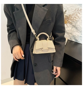 Petit sac bandoulière beige texturé porté par un mannequin en tenue élégante et moderne