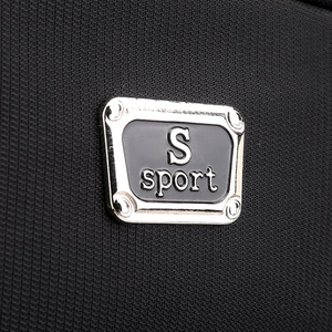 Detail of the high-density nylon fabric and S sport metal logo on a black travel backpack