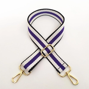 Detail of adjustable purple and white striped woven bag strap with gold metal hooks