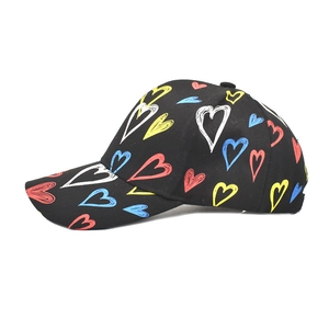 Detail shot of black baseball cap featuring colorful hand-drawn heart graffiti patterns