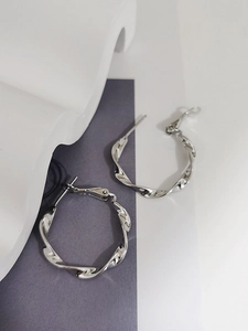 Dettaglio di orecchini a cerchio Mobius in argento con trama lucida su base minimalista