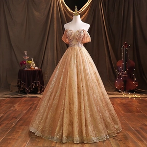 Close-up of champagne gold evening gown with sparkling sequins and sheer puff sleeves