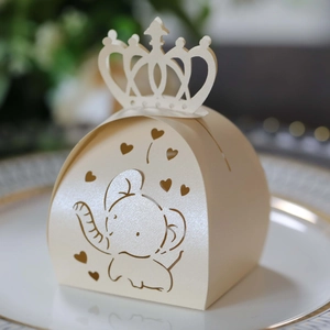 Detailed laser-cut elephant pattern on cream crown-shaped favor box on porcelain plate