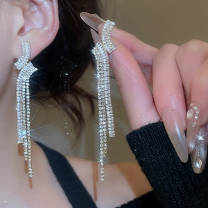 Dettaglio degli orecchini con nappe in argento e zirconi su uno sfondo scuro elegante