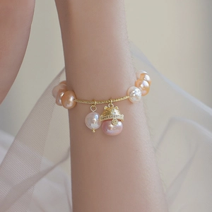 Detail of baroque freshwater pearl bracelet with gold lucky cat charm on wrist