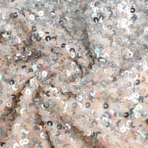 Detailed macro view of sparkling silver sequins on white mesh fabric for party dress