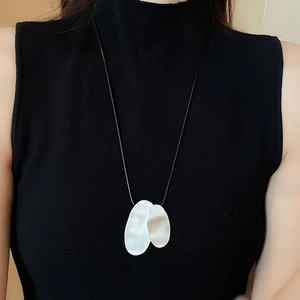 Close-up of minimalist resin flower pendant on a black cord necklace with metallic silver rings