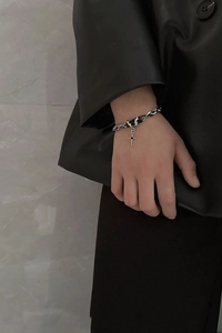 Silver thick chain bracelet with star pendant worn against a grey marble wall